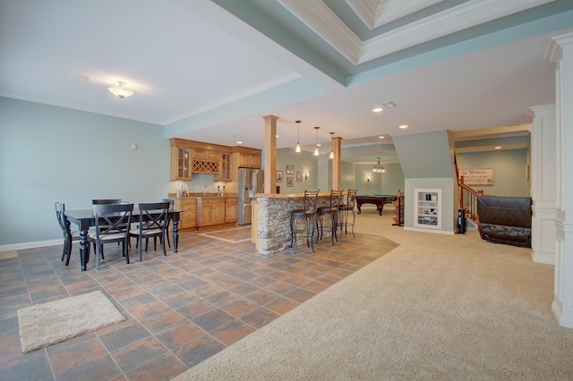 carpeted dining space featuring bar, ornamental molding, and ornate columns