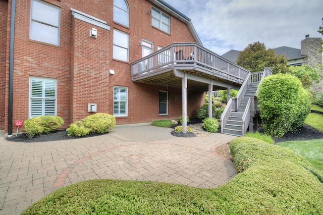 rear view of property with a wooden deck and a patio