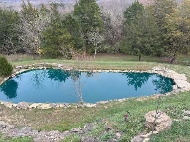 view of pool with a water view and a yard