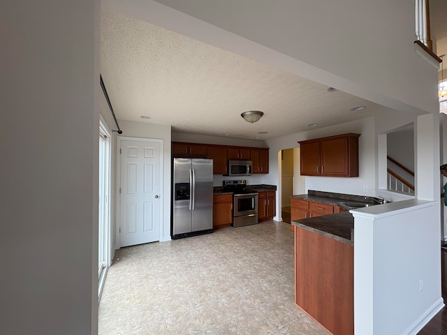 kitchen featuring stainless steel appliances, a healthy amount of sunlight, a textured ceiling, and kitchen peninsula