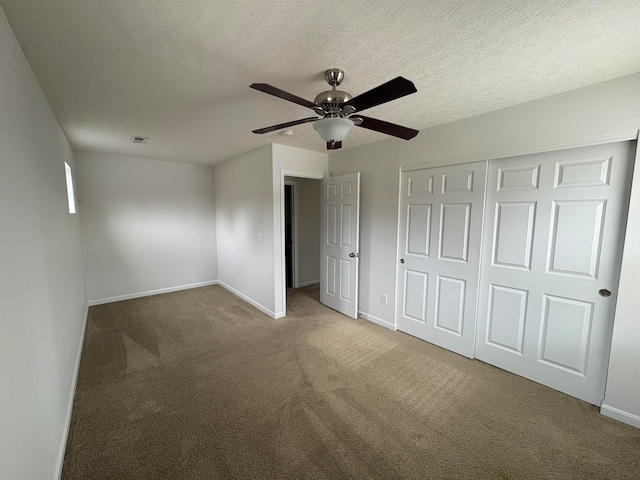 unfurnished bedroom with a textured ceiling, carpet, ceiling fan, and a closet