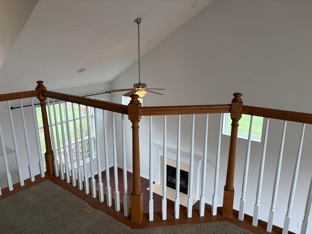 stairway featuring ceiling fan, a high end fireplace, vaulted ceiling, and carpet floors