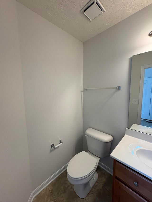 bathroom featuring toilet, vanity, a textured ceiling, and tile patterned floors