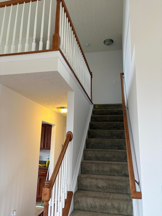 stairs featuring a textured ceiling and hardwood / wood-style flooring