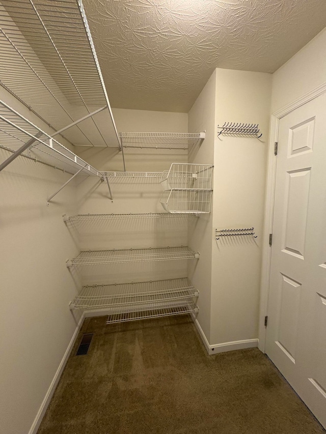 spacious closet featuring dark carpet