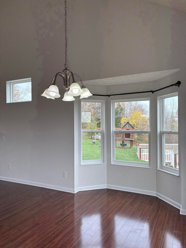 unfurnished room featuring dark wood-type flooring, plenty of natural light, and a notable chandelier