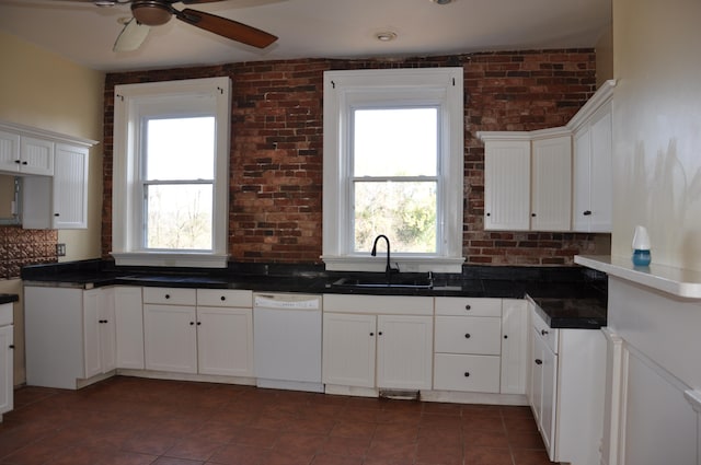 kitchen with white cabinetry, sink, brick wall, white dishwasher, and ceiling fan