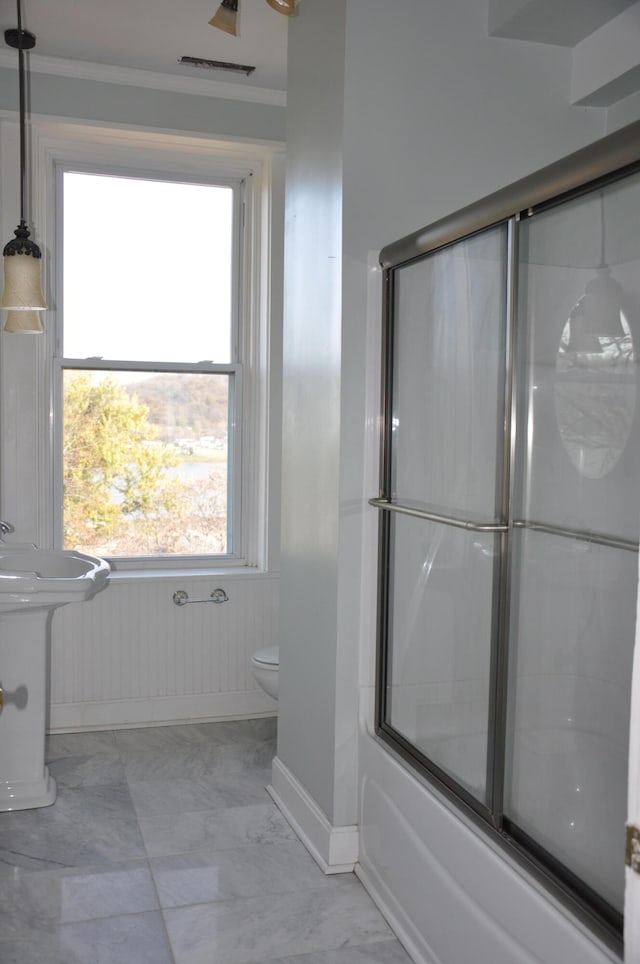 bathroom featuring enclosed tub / shower combo, toilet, and ornamental molding