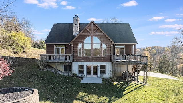 rear view of property featuring french doors, a lawn, and a deck