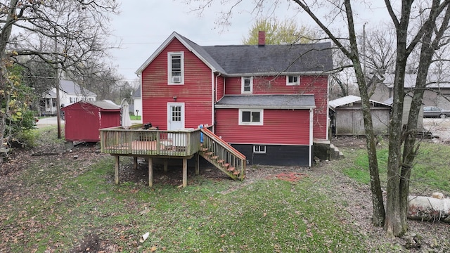 rear view of property featuring a wooden deck and a storage unit