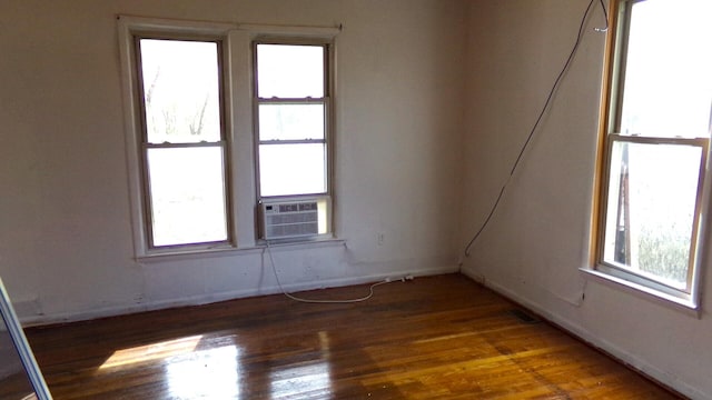 spare room with dark hardwood / wood-style floors, cooling unit, and a healthy amount of sunlight