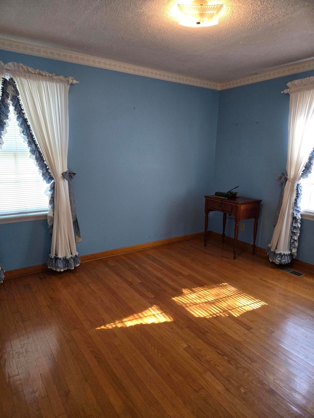 spare room with crown molding, a textured ceiling, and hardwood / wood-style flooring