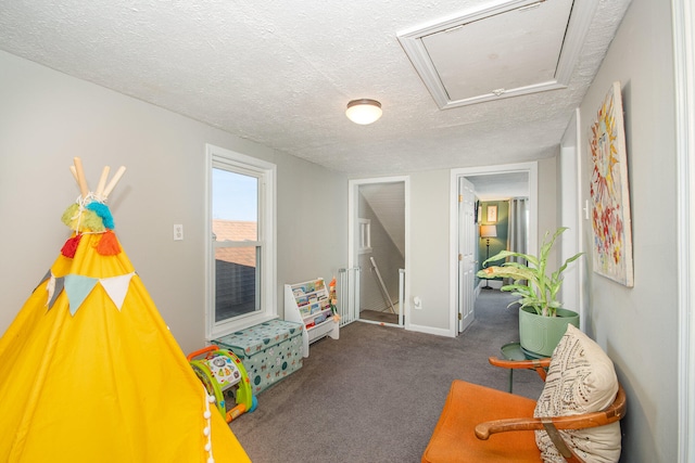 playroom with dark colored carpet and a textured ceiling