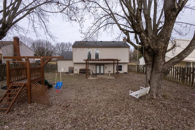 back of house with a fenced backyard, a chimney, and a playground