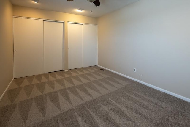 unfurnished bedroom featuring carpet flooring, two closets, visible vents, and baseboards