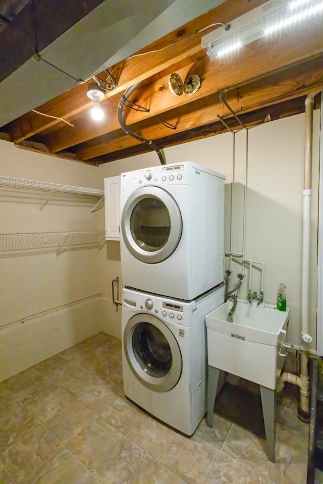 washroom featuring laundry area, stacked washing maching and dryer, and a sink