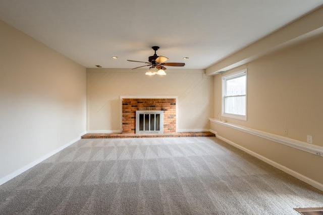 unfurnished living room featuring carpet, a fireplace, baseboards, and a ceiling fan