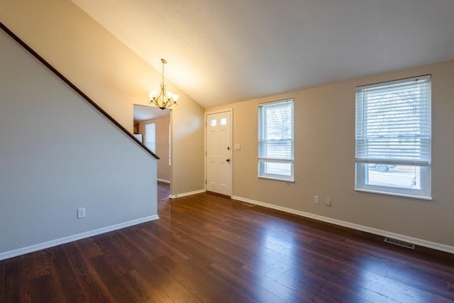 entryway with lofted ceiling, a chandelier, wood finished floors, visible vents, and baseboards