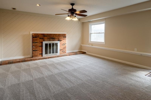 unfurnished living room with carpet floors, wood walls, visible vents, baseboards, and a brick fireplace