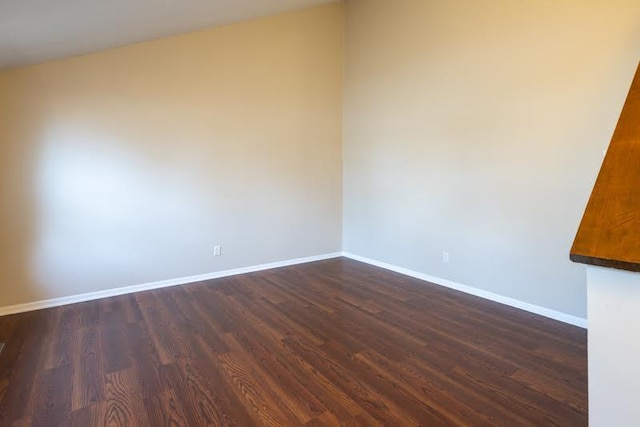 unfurnished room featuring baseboards and dark wood-style flooring