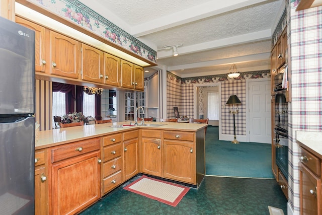 kitchen with sink, kitchen peninsula, stainless steel fridge, a textured ceiling, and dark carpet