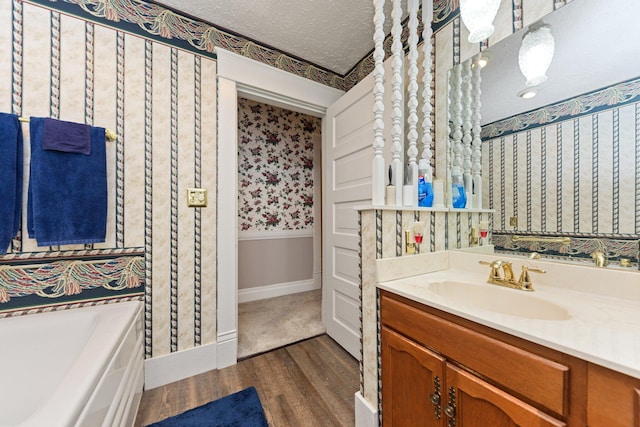 bathroom with a tub, vanity, a textured ceiling, and hardwood / wood-style flooring