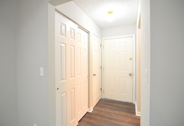 corridor featuring a textured ceiling and dark wood-type flooring