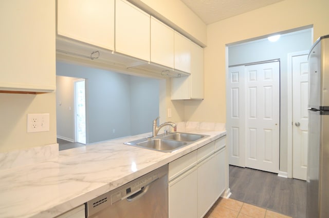 kitchen featuring sink, light stone countertops, a textured ceiling, wood-type flooring, and stainless steel appliances