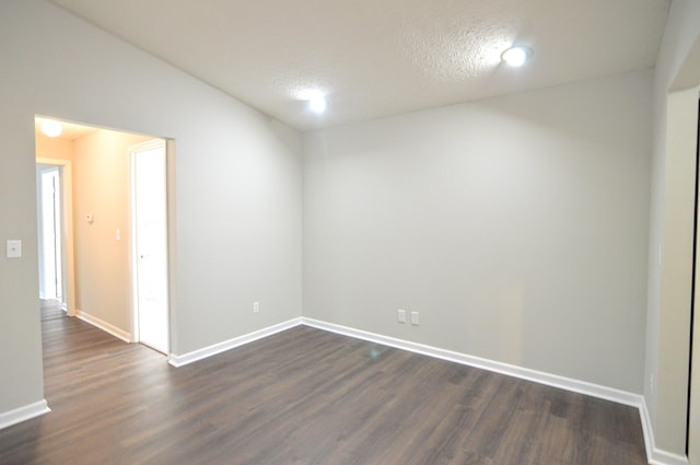 unfurnished room featuring dark wood-type flooring and a textured ceiling