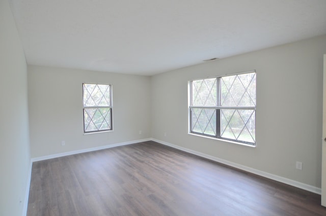 unfurnished room with dark wood-type flooring and a wealth of natural light