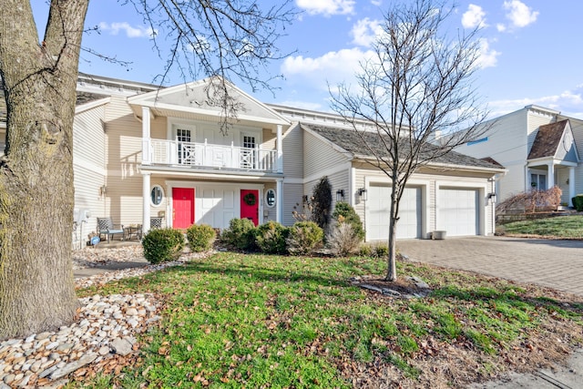 front of property featuring a balcony, a front yard, and a garage