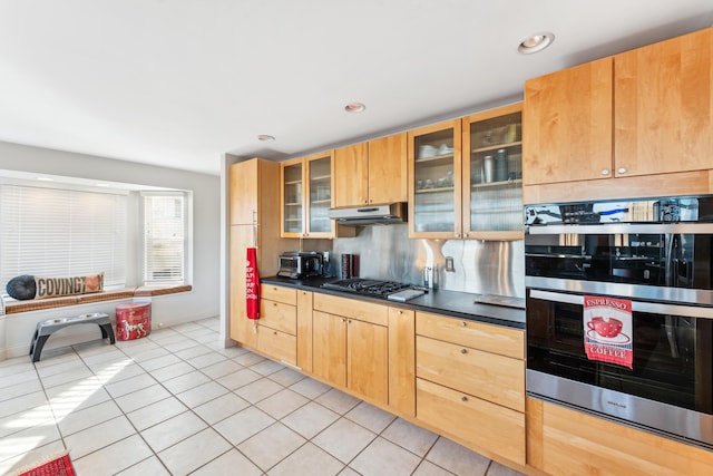 kitchen with tasteful backsplash, light tile patterned flooring, and appliances with stainless steel finishes