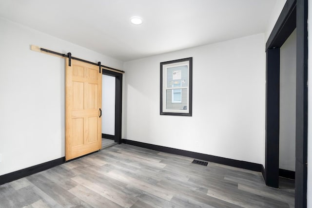 unfurnished bedroom featuring hardwood / wood-style floors and a barn door