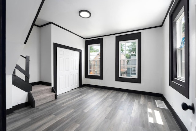 unfurnished bedroom featuring hardwood / wood-style floors, crown molding, and a closet