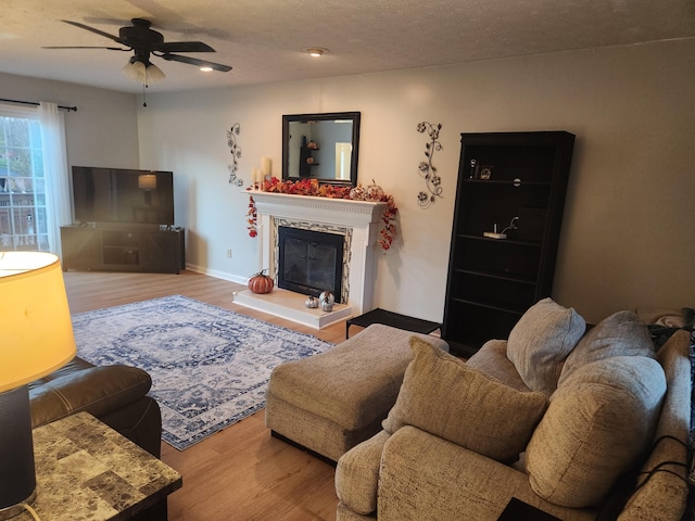 living room featuring a textured ceiling, a premium fireplace, hardwood / wood-style floors, and ceiling fan