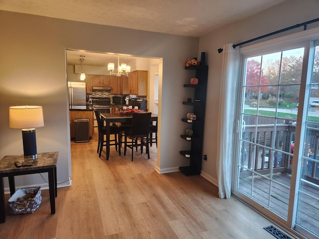 dining room with light hardwood / wood-style floors, a textured ceiling, and a notable chandelier