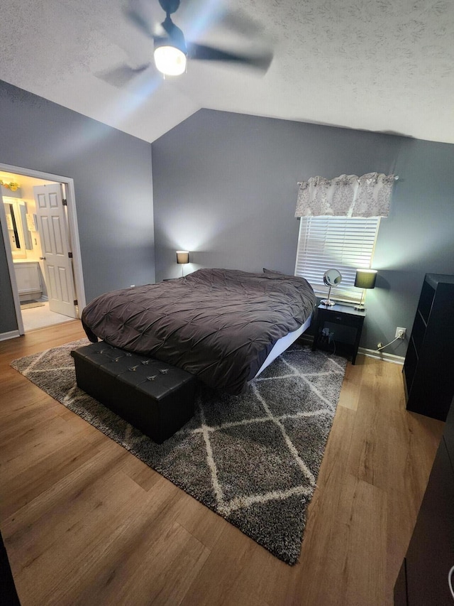 bedroom featuring ensuite bathroom, hardwood / wood-style flooring, ceiling fan, a textured ceiling, and vaulted ceiling