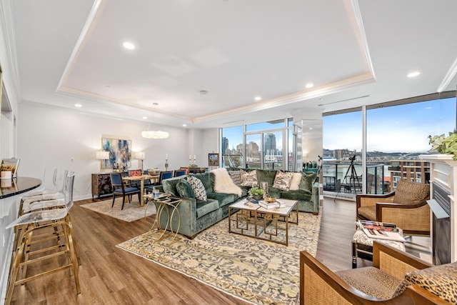 living room with a raised ceiling, a wall of windows, and hardwood / wood-style flooring