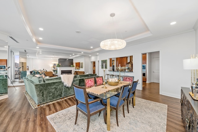 dining space with a tray ceiling, hardwood / wood-style floors, and ornamental molding