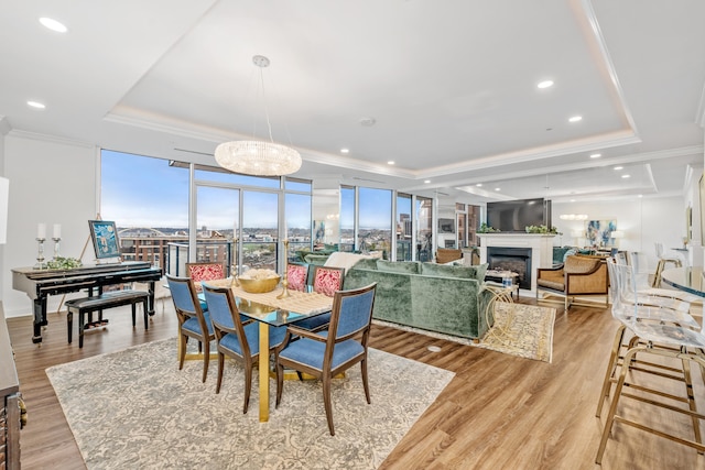 dining space with light hardwood / wood-style floors, a raised ceiling, a wall of windows, and crown molding