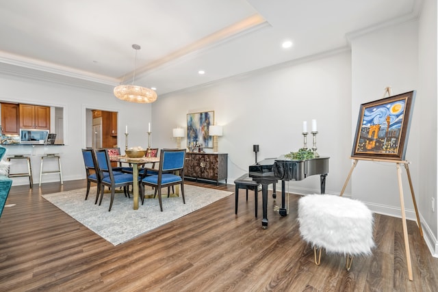 dining space featuring a raised ceiling, crown molding, dark wood-type flooring, and a notable chandelier