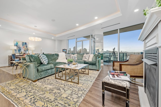 living room with hardwood / wood-style floors, a raised ceiling, floor to ceiling windows, and crown molding