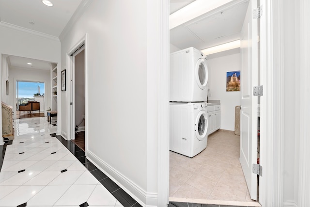 washroom with crown molding, cabinets, light tile patterned floors, and stacked washer / dryer