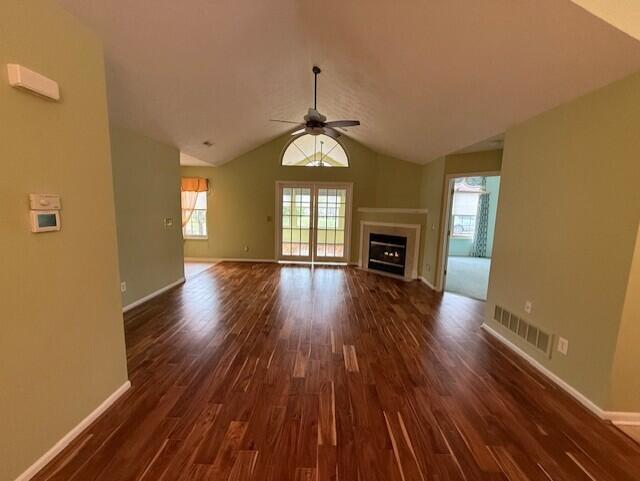 unfurnished living room featuring dark hardwood / wood-style floors, vaulted ceiling, and ceiling fan