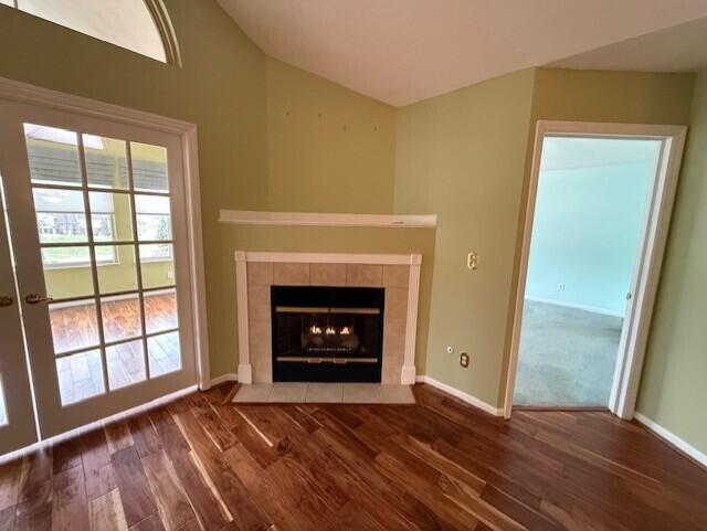 unfurnished living room featuring a fireplace, dark wood-type flooring, and vaulted ceiling