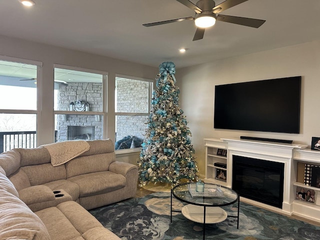 living room featuring a stone fireplace and ceiling fan