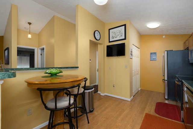 kitchen with kitchen peninsula, decorative light fixtures, light hardwood / wood-style flooring, and lofted ceiling