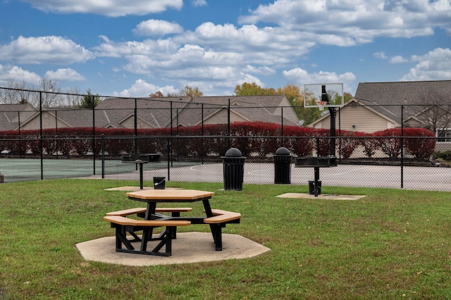 view of home's community with basketball court and a yard