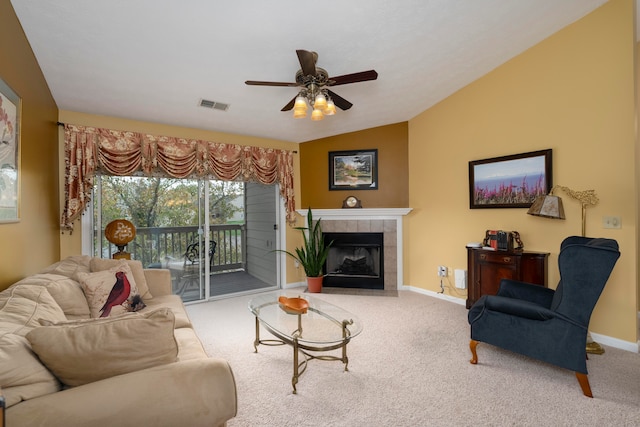 living room featuring ceiling fan, a tiled fireplace, carpet floors, and vaulted ceiling