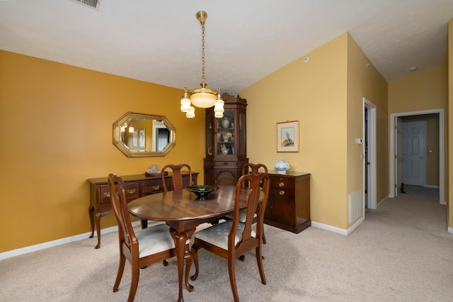 dining area with light carpet, vaulted ceiling, and a notable chandelier